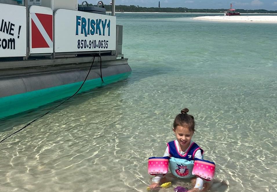 Frisky1 tritoon pulled up to Sand Island beach in Pensacola Beach with a young girl wading in clear water