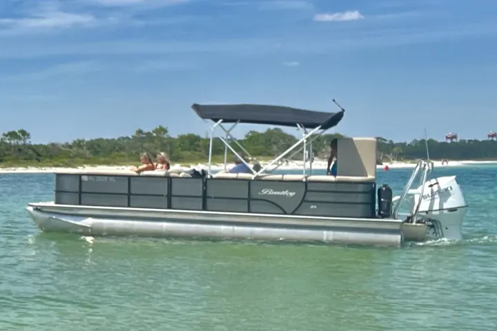 A pontoon boat cruising through clear shallow water in the Santa Rosa Sound near Pensacola Beach, Florida.
