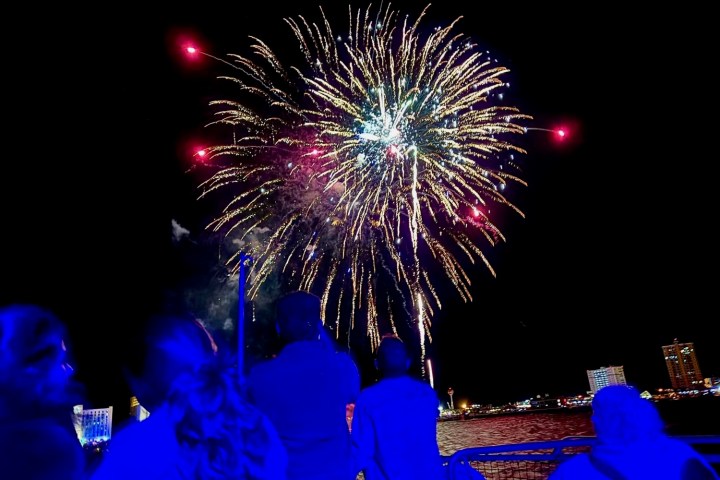 Guests watching fireworks from a dolphin cruise boat during a nighttime tour on Pensacola Bay in Pensacola Beach, Florida
