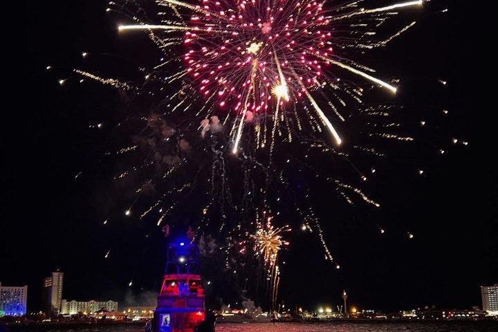 Nighttime fireworks display above a dolphin cruise boat on Pensacola Bay near Pensacola Beach