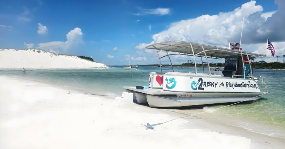 Small boat docked on a sandy beach with clear waters and blue sky.