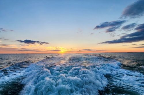 Ocean waves at sunset with a colorful sky and scattered clouds.