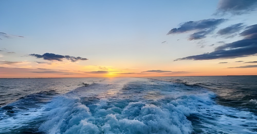 Ocean waves and sunset with clouds in the sky.