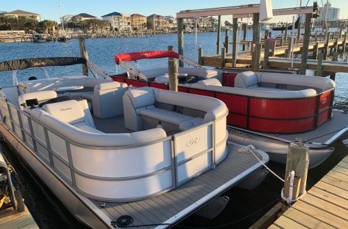 Two pontoon boats docked at a marina on a sunny day.