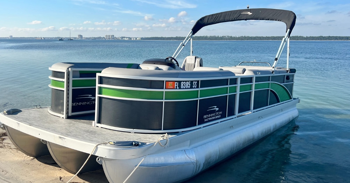 A Frisky Mermaid pontoon rental on Pensacola Beach pulled on a sandy shoreline on Pensacola Bay.