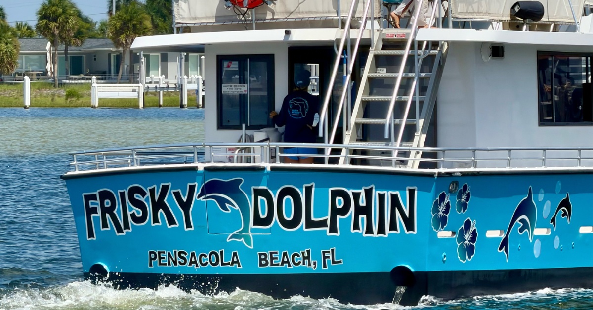 Frisky Dolphin cruise vessel stern showing Pensacola Beach FL lettering and dolphin artwork